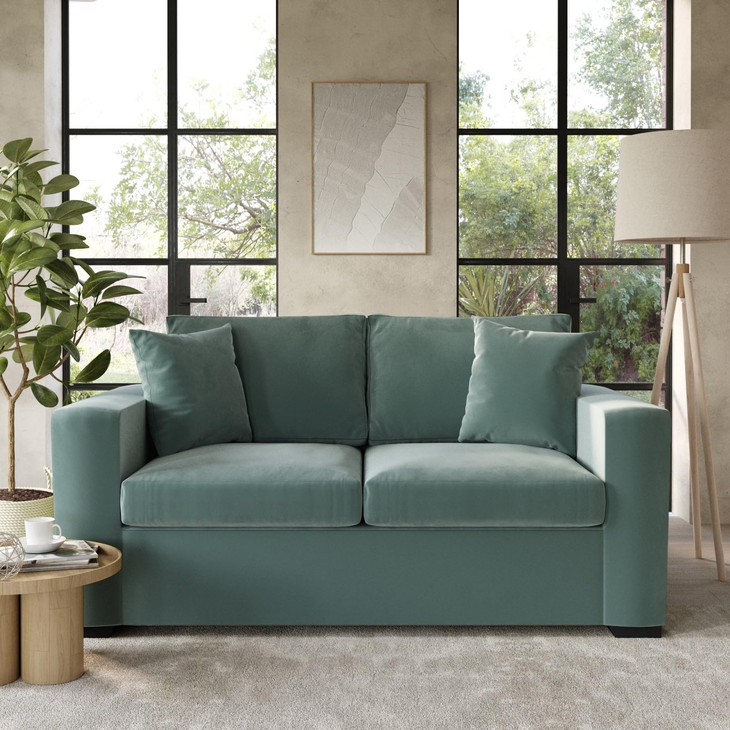 Teal sofa bed in a living room with large windows and a lamp.