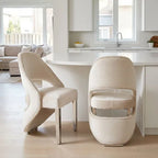 Two modern upholstered dining chairs in a warm cream fabric with a quilted texture, shown in a bright, contemporary kitchen setting.