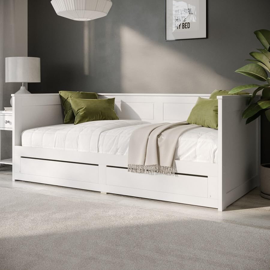White bed with green pillows and a gray blanket in a bedroom setting.