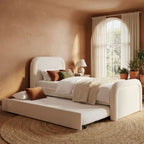 White bed with pull-out trundle in a bedroom with beige walls and large window.
