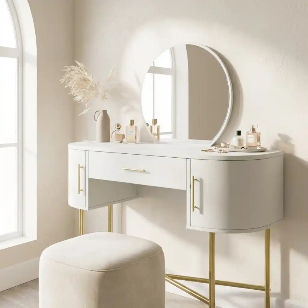 White vanity table with gold legs and a round mirror in a bright room.