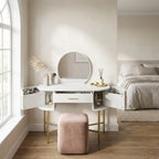 White vanity table with round mirror and pink stool in a bedroom setting