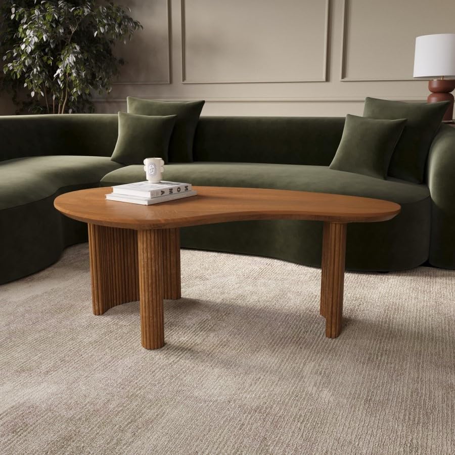 Wooden coffee table in front of a green sofa with decorative items on a beige carpet.