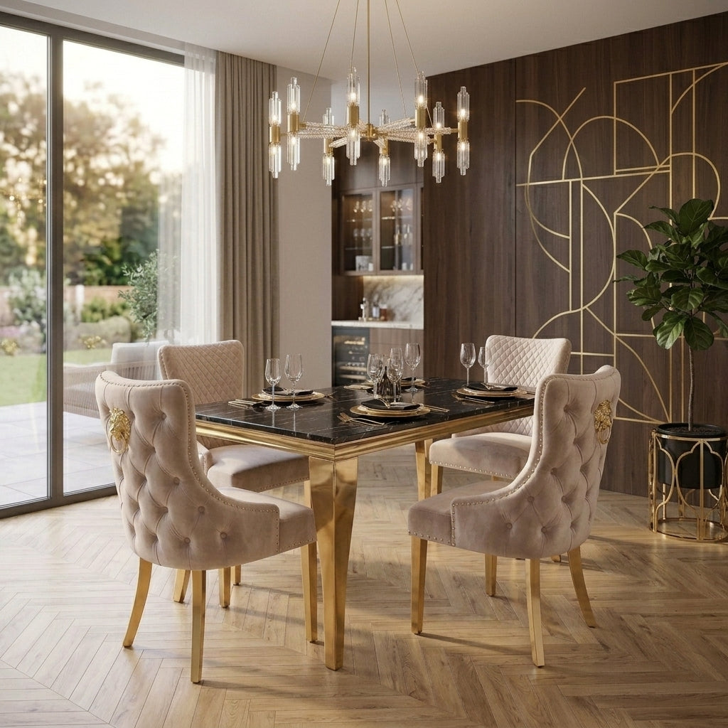 A luxury dining room set featuring a rectangular black marble-top table with a gold frame, surrounded by four tufted blush pink velvet chairs with gold accents. The room is styled with a modern chandelier, wood herringbone flooring, and a dark wood accent wall with gold geometric lines.