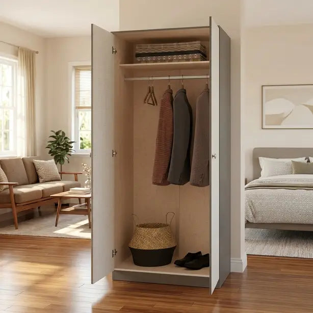 organizer stands open in a staged bedroom/living space. The cabinet has a light gray exterior and beige interior, with a hanging rod holding three garments, a folded stack on top, and a woven basket and shoes on the bottom shelf.