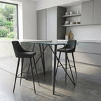 Modern kitchen with a glass island and black bar stools.