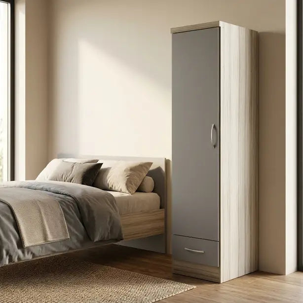 A compact modern wardrobe with a light wood grain finish and a matte gray door, shown next to a bed in a minimalist bedroom setting.