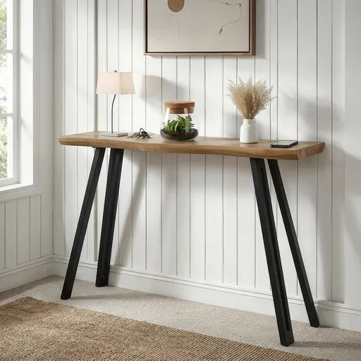 A console table with a light brown wood top and black metal A-frame legs, 