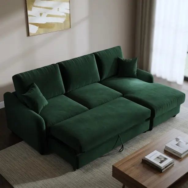 A dark green velvet sectional sofa with a chaise lounge, styled in a modern living room setting with a wooden coffee table, neutral rug, and soft window light.