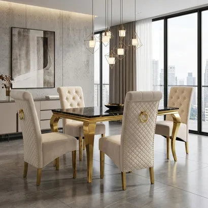 A luxury dining room set featuring a rectangular black marble-top table with gold legs, surrounded by four high-back cream tufted velvet chairs with gold legs and ring pulls, set in a modern high-rise apartment.