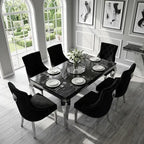A modern dining room set featuring a rectangular black marble-top table with silver legs and six black upholstered chairs with silver nailhead trim, set in a bright, contemporary dining room.