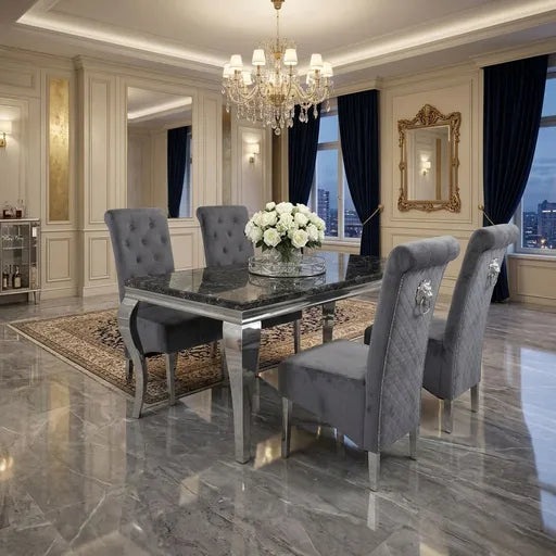 A luxury dining room set featuring a rectangular dark marble-top table with a polished chrome frame, surrounded by four high-back gray tufted velvet chairs with silver legs, set on a patterned area rug in a grand room with dark blue curtains and a crystal chandelier.