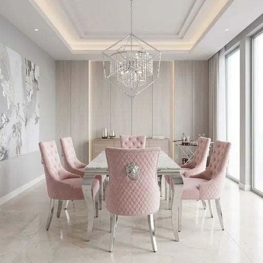 A modern dining room set featuring a rectangular glass-top table surrounded by six tufted pink velvet chairs with silver metal legs and backs, set under a geometric crystal chandelier in a bright, contemporary dining room.