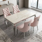 A modern dining set featuring a rectangular table with a cream marble-patterned top and chrome legs, surrounded by four pink tufted and quilted velvet chairs with silver metal legs, set in a contemporary dining room.
