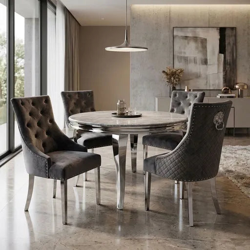 A luxury dining set featuring a round marble-top table and four high-back tufted velvet dining chairs in dark gray, styled in a modern, elegantly decorated dining room.