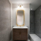 Bathroom with wooden vanity, marble countertop, and gold-framed mirror.