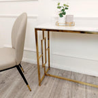 Gold desk with white surface and plant against a white wall