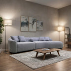 Modern living room with a gray sectional sofa, wooden coffee table, and abstract art on the wall.