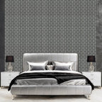 Gray upholstered bed with decorative pillows against a gray brick-patterned wall.