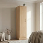 A tall, light oak wood wardrobe with a single door and a bottom drawer, styled in a minimalist bedroom setting.