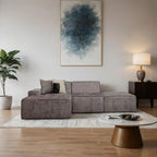 Modern living room with a gray sectional sofa, round coffee table, and abstract art on the wall.