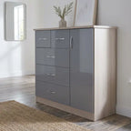 A modern 5-drawer chest of drawers in a gray and light wood finish, styled in a bright room with a mirror, framed art, and a woven rug.