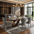 A luxury dining room set featuring a rectangular marble-top dining table with a sculptural bronze base, surrounded by six tufted gray fabric chairs with lion head backrests, set on a gray rug in a modern dining room.