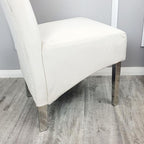 Cream chair with chrome legs on a wooden floor against a gray wall