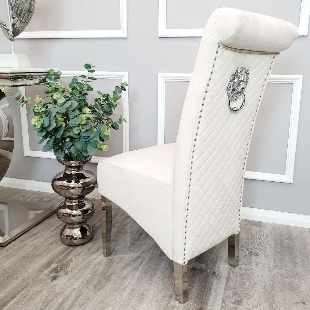 Cream upholstered chair with decorative backrest in a room with framed pictures on the wall.