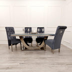 Dining table set with four gray chairs in a room with white walls and wooden flooring.