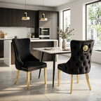 Two black upholstered dining chairs with tufted backs, nailhead trim, and gold legs, shown around a table in a modern kitchen and dining room setting.