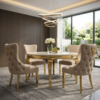A luxury dining set featuring a round marble-top table with a gold metallic base and six matching tufted beige velvet chairs with gold accents, set in a modern dining room with a slatted wood wall and large windows.