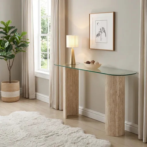 A modern console table with a curved clear glass top and two textured light wood cylindrical legs, 