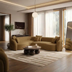 A modern curved sectional sofa in a warm camel-brown color, styled in a luxurious, contemporary living room with a striped rug, wooden coffee table, and large windows with sheer curtains.