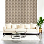 Modern living room with a white sofa, coffee tables, and a plant against a geometric-patterned wall.