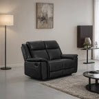 Black leather recliner sofa in a modern living room setting with a lamp and wall art.