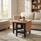 A rustic drop-leaf coffee table with a light wood top and dark black legs, styled in a bright living room next to a beige sofa.