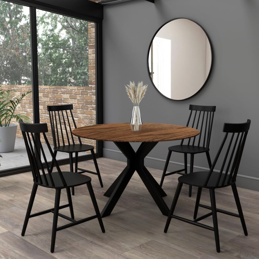 Dining room with a wooden table and black chairs against a gray wall with a round mirror.